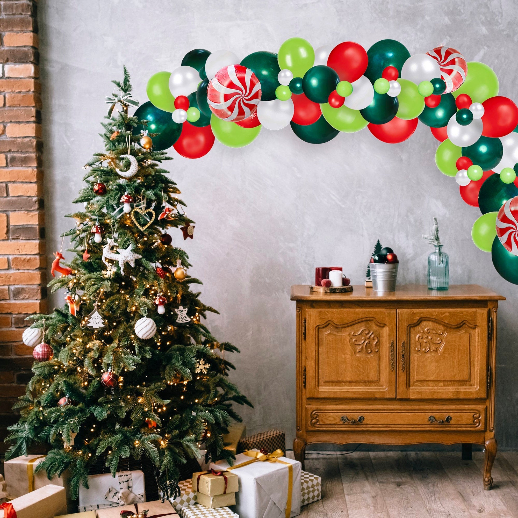 Decorated Christmas tree with balloons and a wooden cabinet in a room.