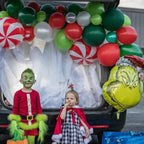 Two children in festive costumes sitting in a decorated car trunk with balloons and decorations.