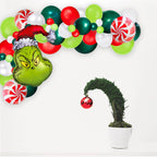 Decorative setup with balloons shaped like the Grinch and a potted plant with a Christmas ornament.