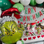 Decorative setup with 'Merry Grinchmas' banner, balloons, and festive decorations.