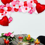 Decorative table setting with heart-shaped balloons and a floral arrangement.