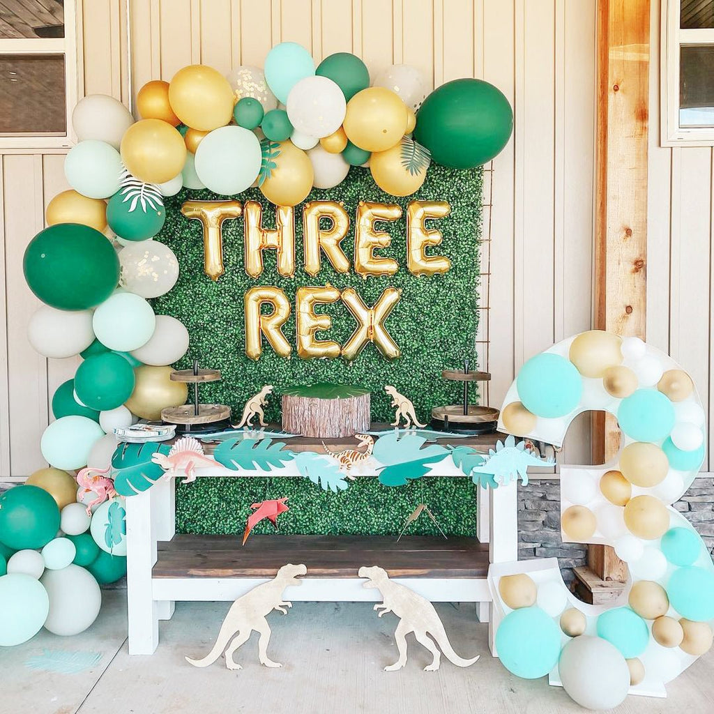 Decorative setup with balloons and 'THREE REX' balloons for a themed event.