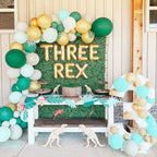 Decorative setup with balloons and 'THREE REX' balloons for a themed event.