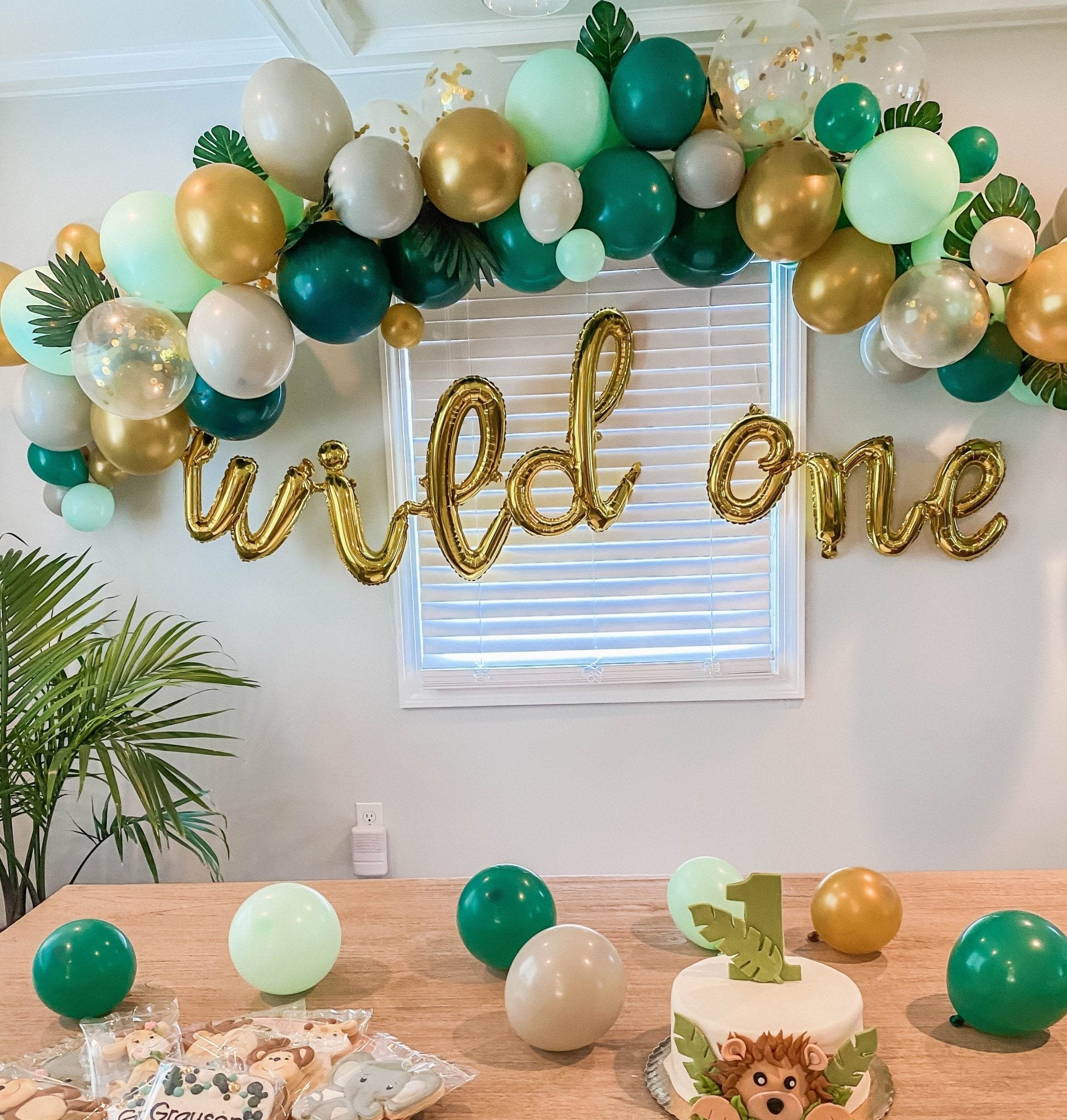 Decorated room with balloons, cake, and 'wild one' banner for a first birthday party. Main image