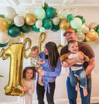 Family of five celebrating a child's first birthday with balloons and decorations.