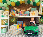 Child's first birthday party setup with balloons, decorations, and a toy car.