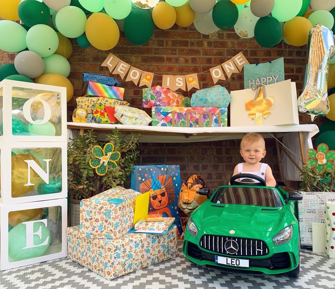 Child's first birthday party setup with balloons, decorations, and a toy car.