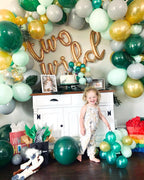 Child in a decorated room with balloons and 'Two Wild' sign