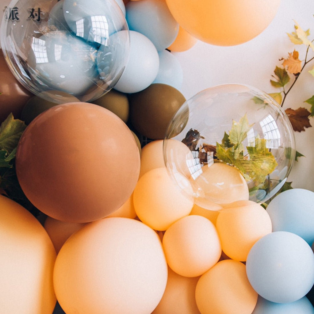 Colorful balloons with transparent bubbles containing greenery against a blurred indoor background.