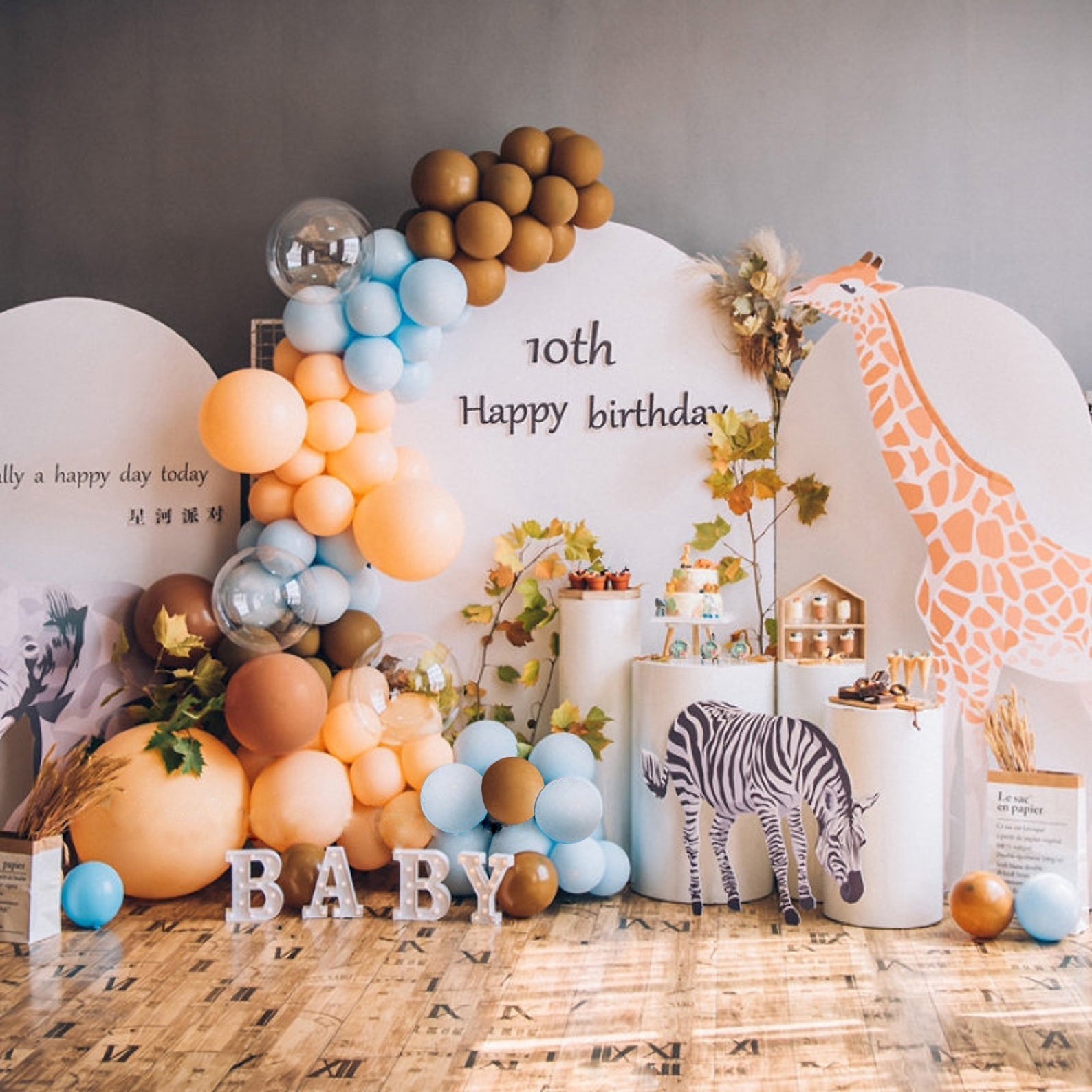 Birthday party setup with balloons, a giraffe decoration, and '10th Happy Birthday Baby' sign.